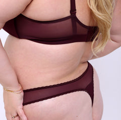 Load image into Gallery viewer, Size 2XL model showing back view of black cherry mid rise thong in organic cotton fabric with sexy mesh panels
High cut leg, non-toxic lace trim, breathable cotton fabric