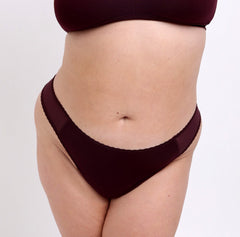 Load image into Gallery viewer, Size 2xl model wearing black cherry mid rise thong in organic cotton fabric
Sexy high cut leg, non-toxic lace trim, breathable cotton fabric