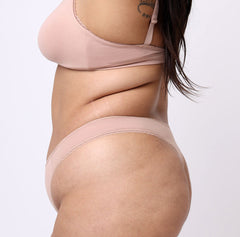 Load image into Gallery viewer, Size L model side view of beige chamapgne color mid rise thong in organic cotton fabric
Sexy high cut leg, non-toxic lace trim, breathable cotton fabric