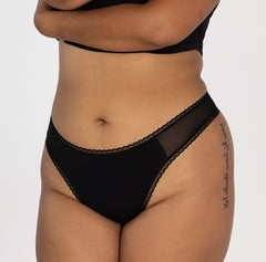 Load image into Gallery viewer, model wearing la coochie organic cotton mid rise thong underwear in midnight black, best mid rise waist thong option
