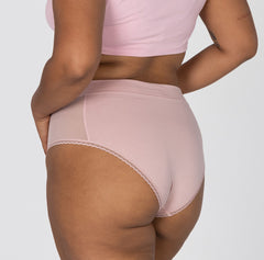 Load image into Gallery viewer, Side and back view of woman wearing high rise organic cotton brief underwear in blush pink featuring lace detail and soft waistband