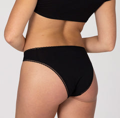 Load image into Gallery viewer, Size small model showing back/butt view of mid rise brief underwear in la coochie organic cotton brief, all-cotton midnight black style
