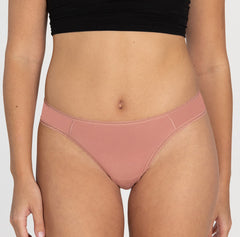 Load image into Gallery viewer, Size small model facing front wearing organic cotton underwear in mid rise brief style, featuring desert rose pink color
