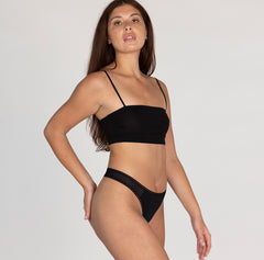 Load image into Gallery viewer, Size small model wearing organic cotton mid rise thong underwear in midnight black, showing lace detail and side high cut leg

