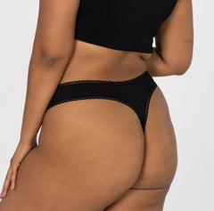 Load image into Gallery viewer, model facing back to show off la coochie mid rise organic cotton thong, features lace detail and sexy curved thong back for flattering look
