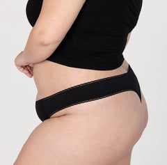 Load image into Gallery viewer, XXL model showing off side of la coochie organic cotton mid rise thong in midnight black, shows high cut leg and never too tight waistband for a comfortable fit
