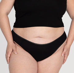 Load image into Gallery viewer, XXL model wearing mid rise thong from la coochie in midnight black color, high cut leg and lace details for feminine look