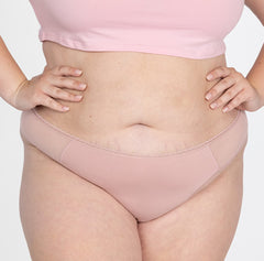 Load image into Gallery viewer, XXL model wearing la coochie organic cotton mid rise thong in blush pink color, shows flexible fit and lightweight fabric for breathability
