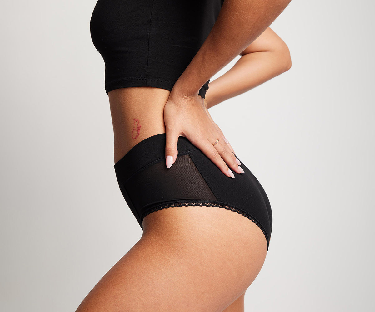 woman wearing certified organic cotton high rise brief in midnight black (featuring non-toxic mesh panels)