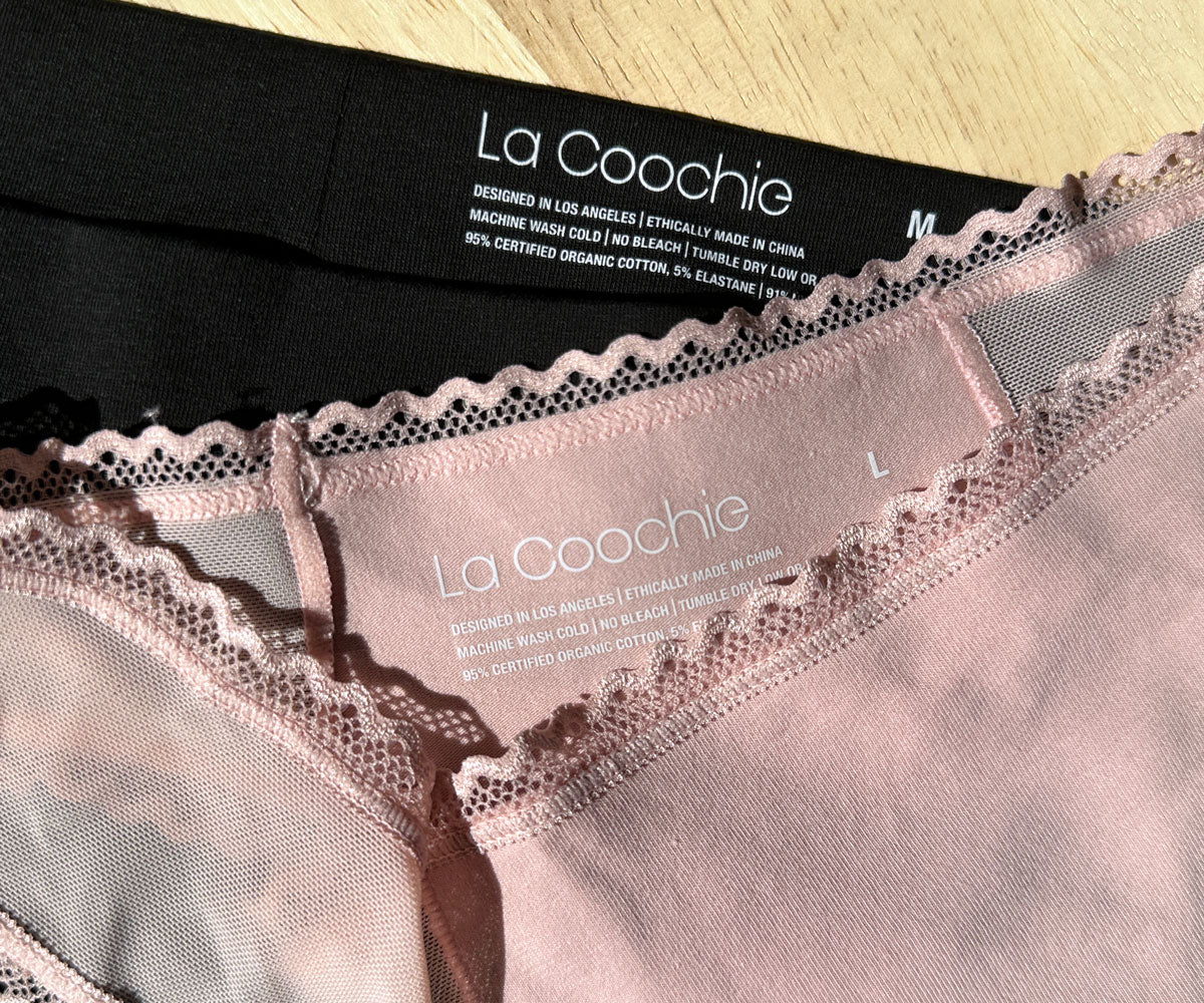 Two pairs of certified organic cotton panties in blush pink and black featuring non-toxic lace trim
