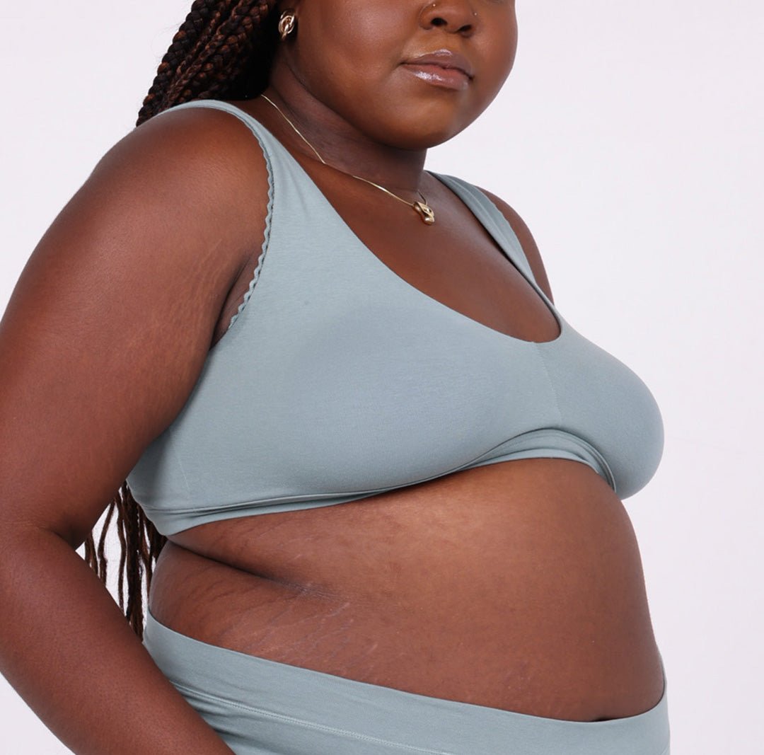 Size 2xl Woman showing side view of sage organic cotton scoop bralette with lace detail and no wire