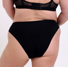 Load image into Gallery viewer, 2XL model showing back view of certified organic cotton mid rise brief in black. Showing cheeky coverage, sexy non-toxic soft lace trim detail &amp; breathable fabric.
