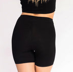 Size S woman showing back view of high rise organic cotton boxer in midnight black. Full coverage, no side seams, lace trim on the leg