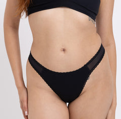 Load image into Gallery viewer, Woman showing front view of Certified Organic cotton mid rise black thong with lace detail
Sexy non-toxic mesh panels and lace trim
