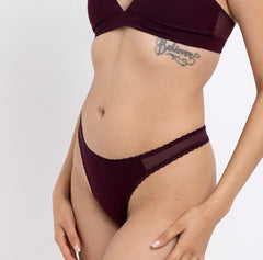 Load image into Gallery viewer, Size XS model showing front view of black cherry mid rise thong in organic cotton fabric 
Sexy high cut leg, non-toxic lace trim, breathable cotton fabric
