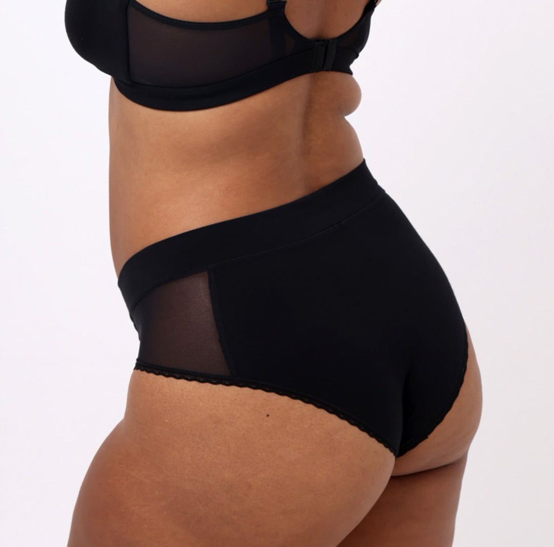 Size L model showing back view of black high rise brief in certified organic cotton fabric 
No side seams, elastic-free waistband, non-toxic lace trim, cheeky coverage