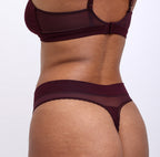 Woman showing back view of black cherry soft, breathable certified organic cotton high rise thong 