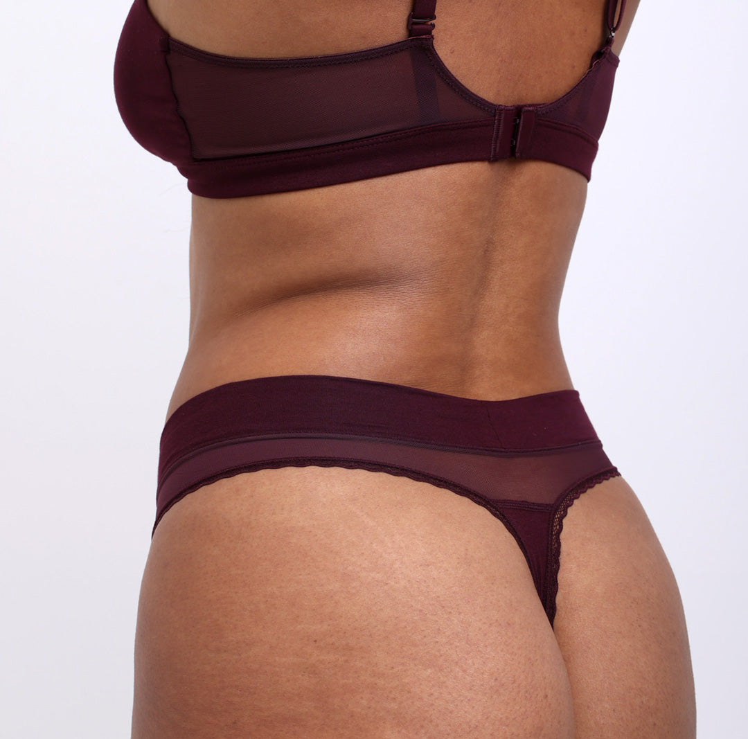 Woman showing back view of black cherry soft, breathable certified organic cotton high rise thong 