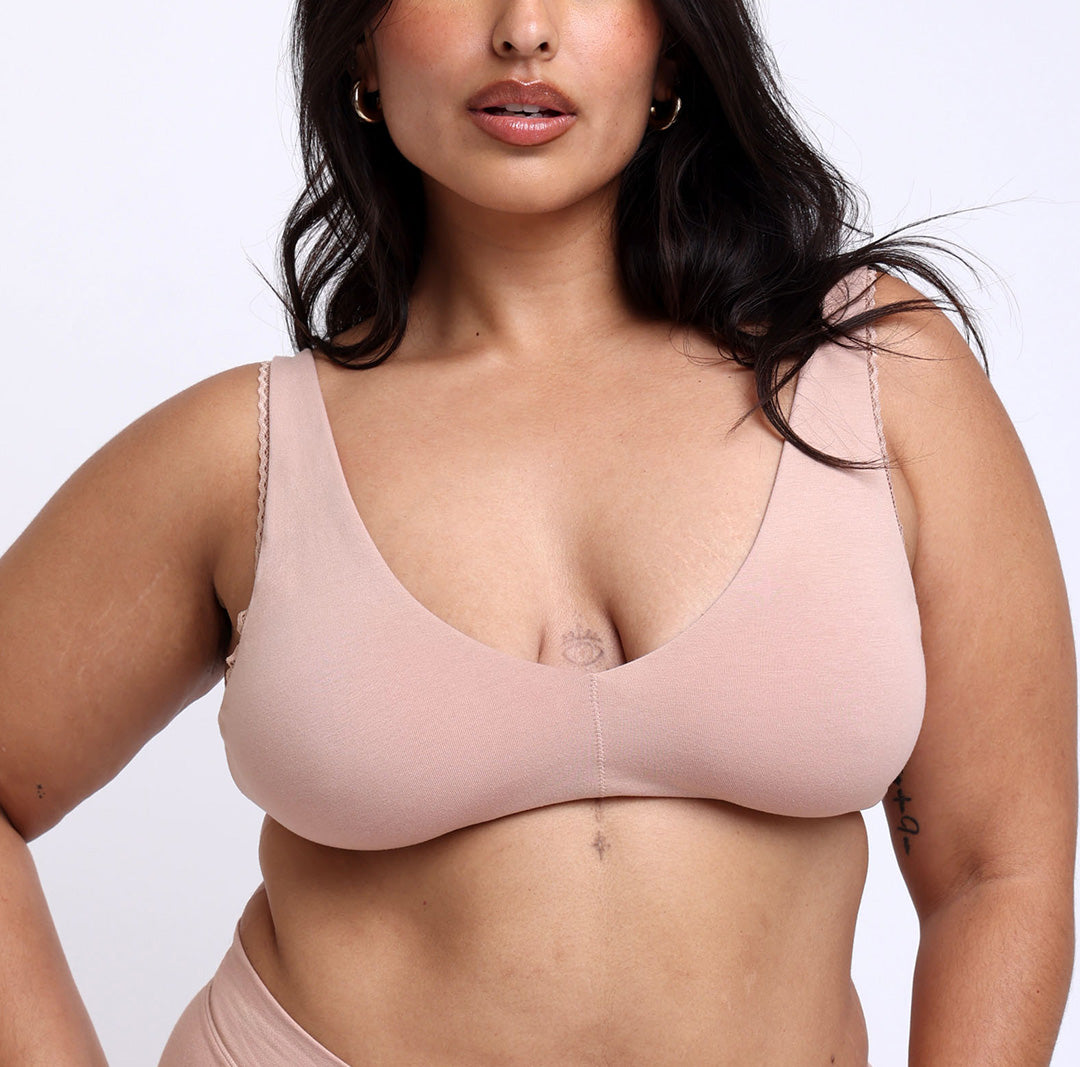 Size large Woman showing front view of soft organic cotton scoop bralette in nude beige champagne color