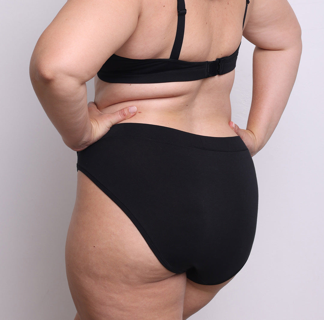 Size L model showing back view of organic cotton French-cut high brief in midnight black. Breathable, super soft organic cotton with a high French-cut leg