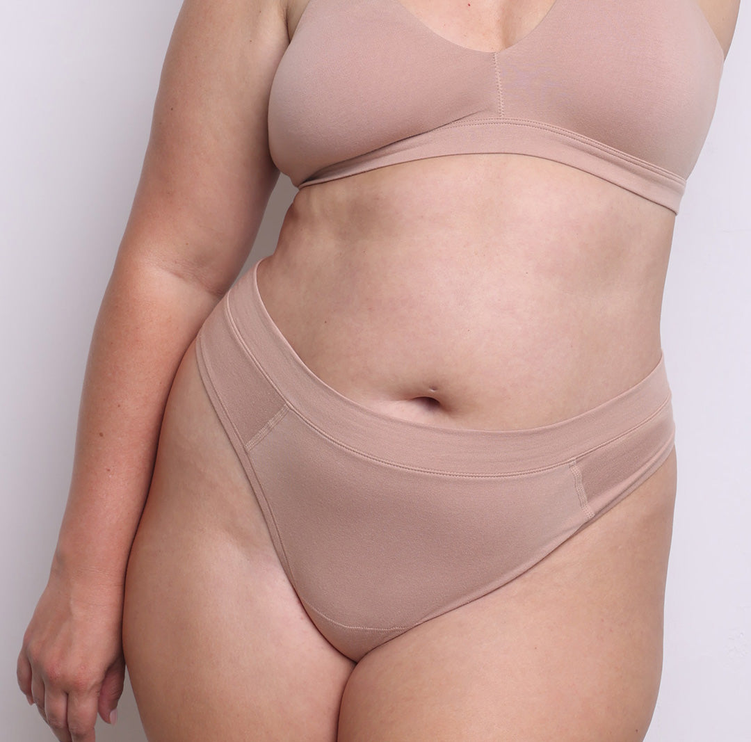 Size L model showing front view of organic cotton high leg thong in champagne. High-cut leg, soft elastic-free waistband and a sewn-down longer gusset