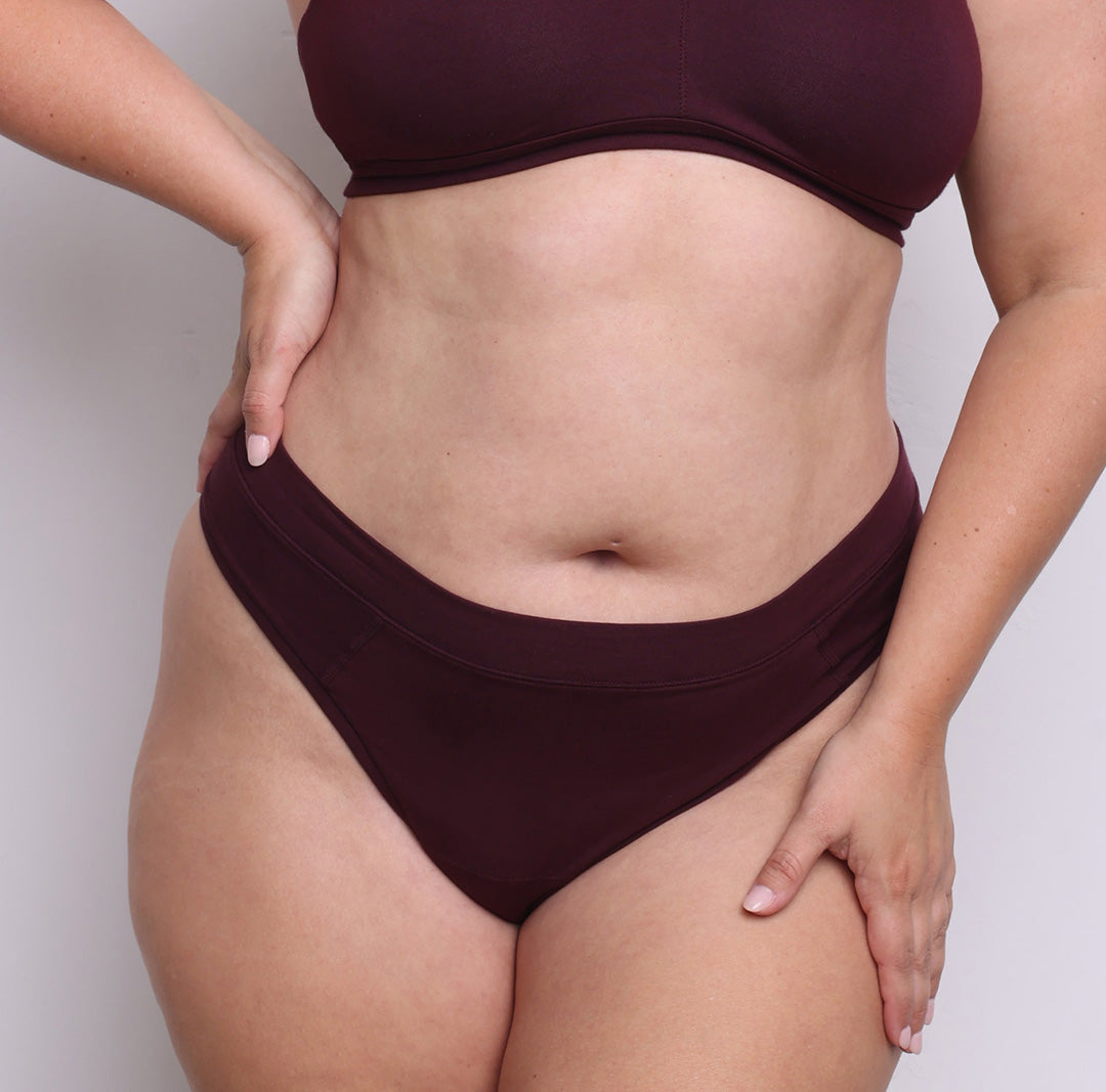 Size L model showing front view of organic cotton high leg thong in black cherry. High-cut leg, soft elastic-free waistband and a sewn-down longer gusset
