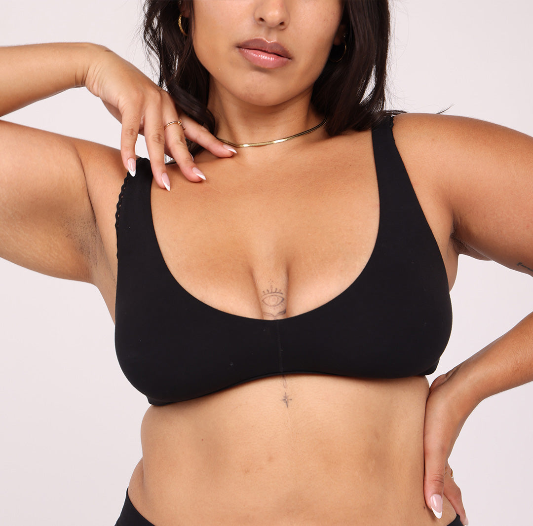 Size large Woman showing front view of soft organic cotton scoop bralette in midnight black with lace detail
