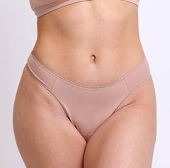 Load image into Gallery viewer, Size S model showing front view of champagne nudge color mid rise thong in organic cotton fabric 
Sexy high cut leg, non-toxic lace trim, breathable cotton fabric
