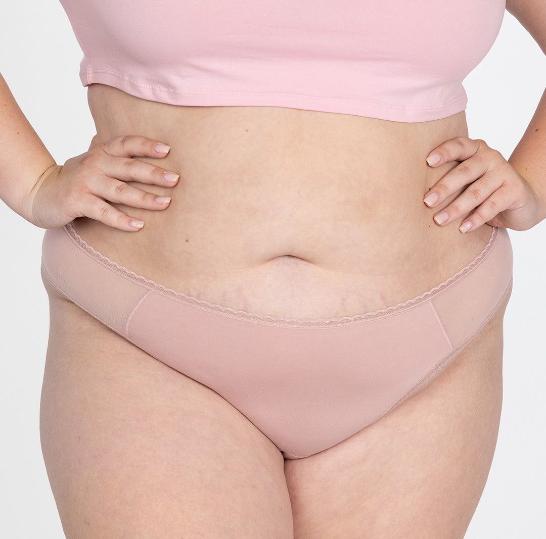 XXL model wearing la coochie organic cotton mid rise thong in blush pink color, shows flexible fit and lightweight fabric for breathability