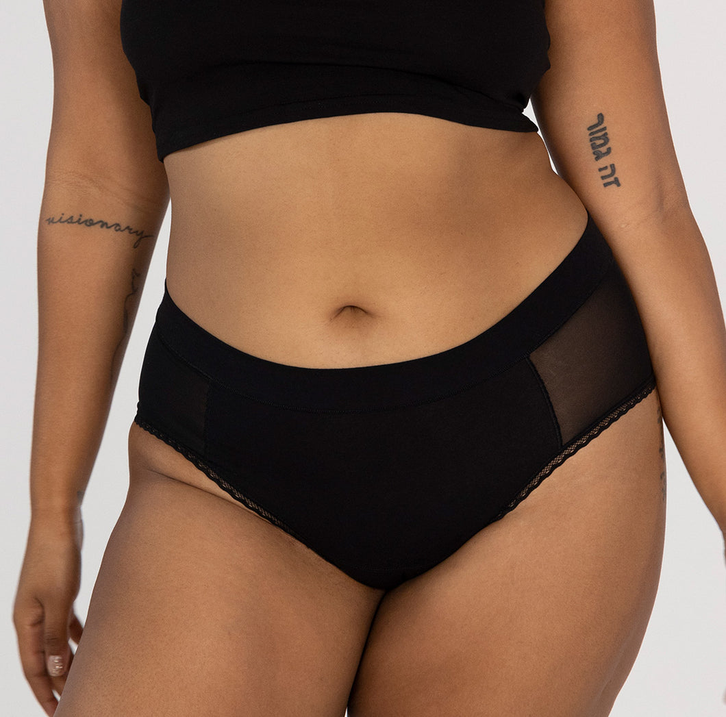 Front view of woman wearing high rise organic cotton briefs in black featuring mesh side panels and soft waistband