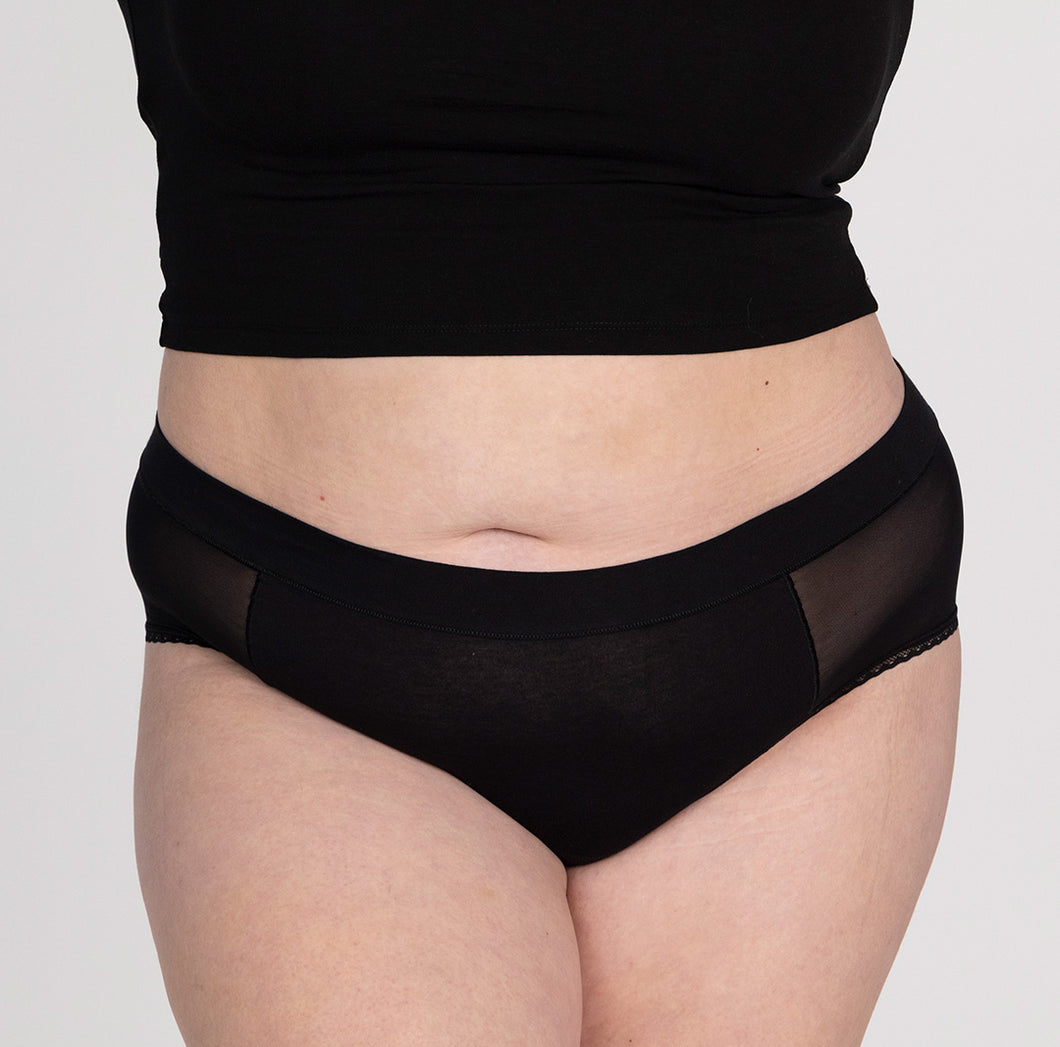 Front view of XXL woman wearing organic cotton high rise brief underwear in black featuring mesh panels