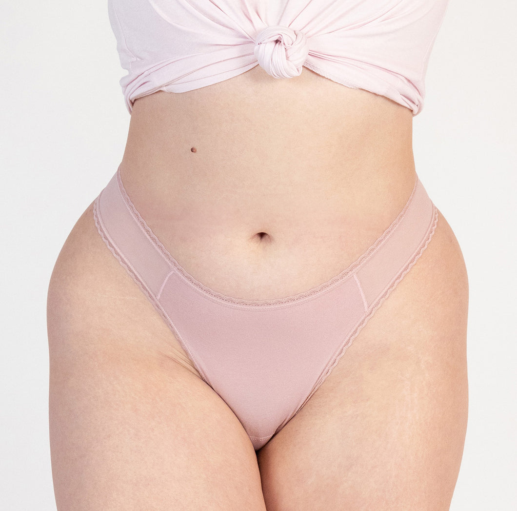 model wearing blush pink organic cotton mid rise thong with high cut sides, wearing blush pink color with mesh panel detail